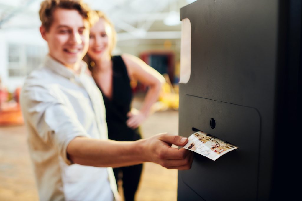 Man and woman collecting their print out images from branded photo booth